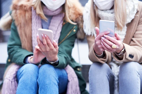 两个女人在城市里使用智能手机和戴口罩 — 图库照片