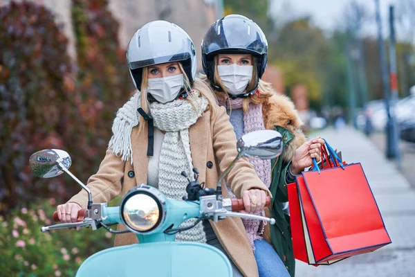 Dwie kobiety w maskach i trzymające torby na skuterze — Zdjęcie stockowe