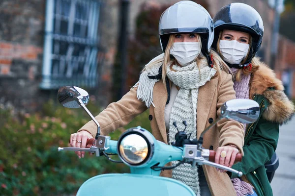 Due donne che indossano maschere e pendolarismo su scooter — Foto Stock