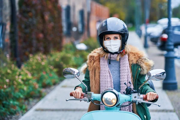 Yetişkin bir kadın maske takıyor ve scooter kullanıyor. — Stok fotoğraf