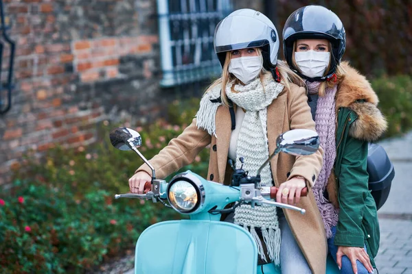 İki kadın maske takıyor ve scooter kullanıyor. — Stok fotoğraf