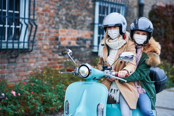 Due donne che indossano maschere e pendolarismo su scooter — Foto Stock