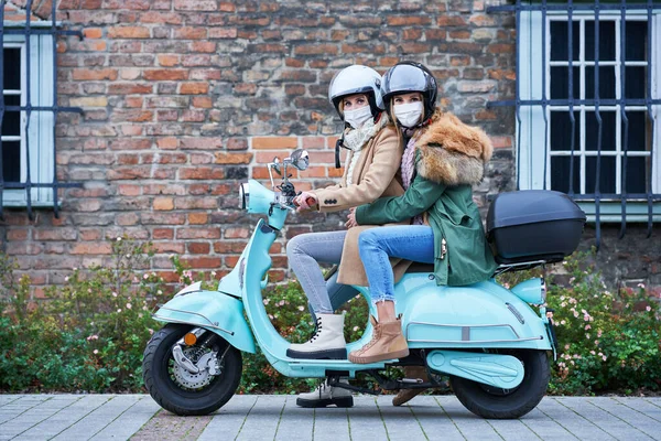 Due donne che indossano maschere e pendolarismo su scooter — Foto Stock