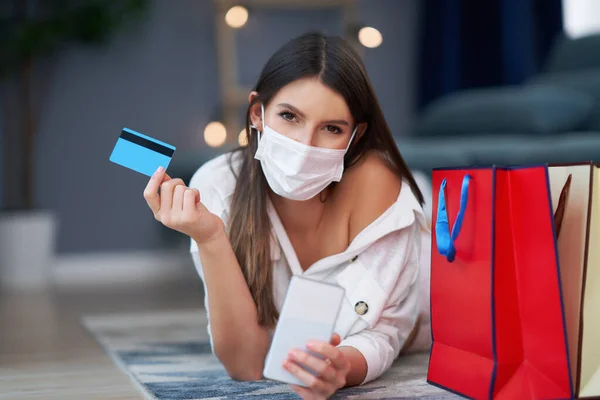 Όμορφη γυναίκα σε μάσκα ψώνια σε απευθείας σύνδεση με πιστωτική κάρτα — Φωτογραφία Αρχείου