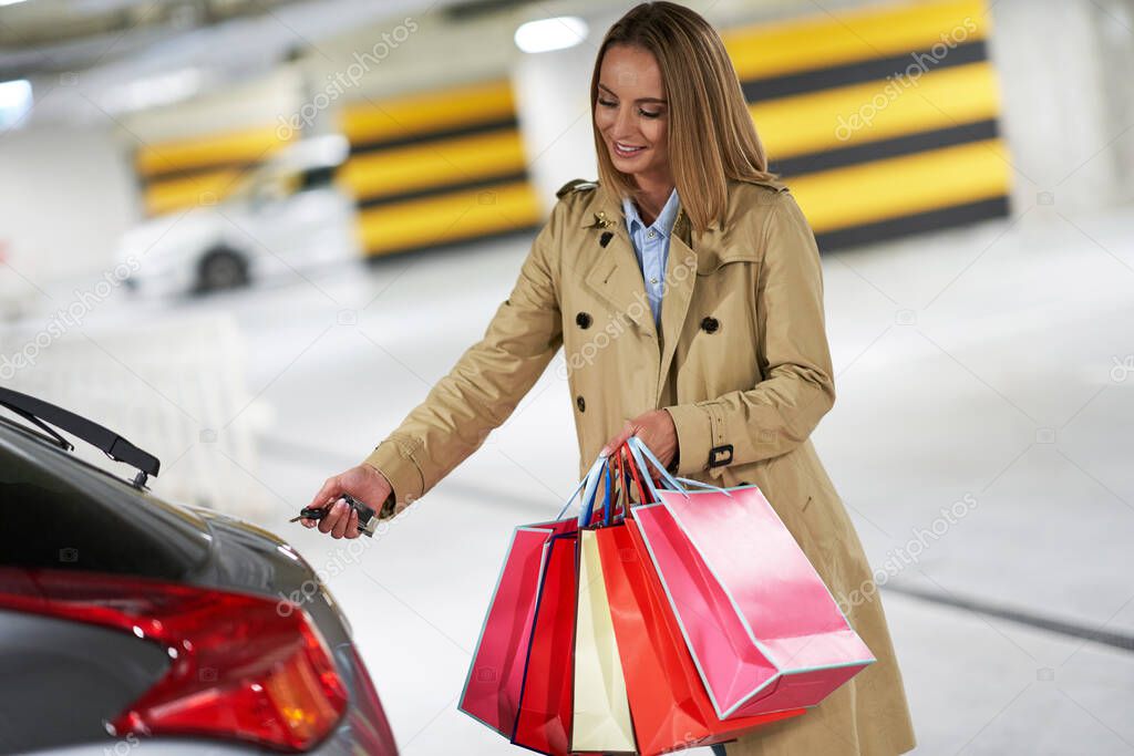 Adult woman with shopping bags in underground parking lot