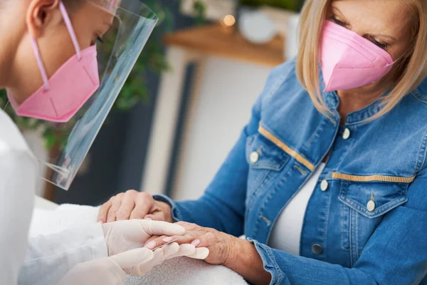 Señora mayor con una máscara en el salón de manicura — Foto de Stock