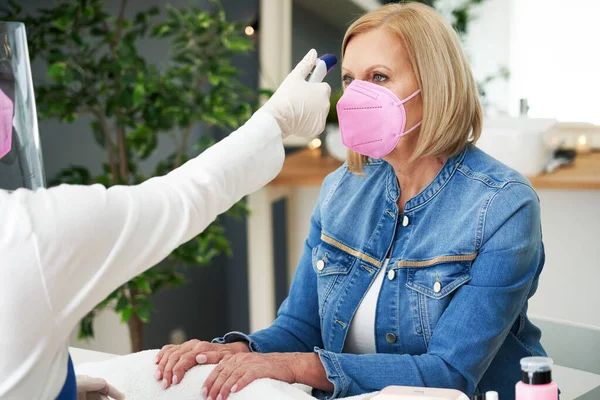 Senior lady wearing a mask in manicure salon — Stock Photo, Image