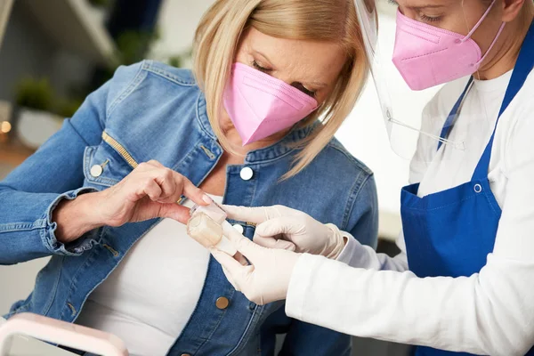 Senior lady wearing a mask in manicure salon — Fotografia de Stock