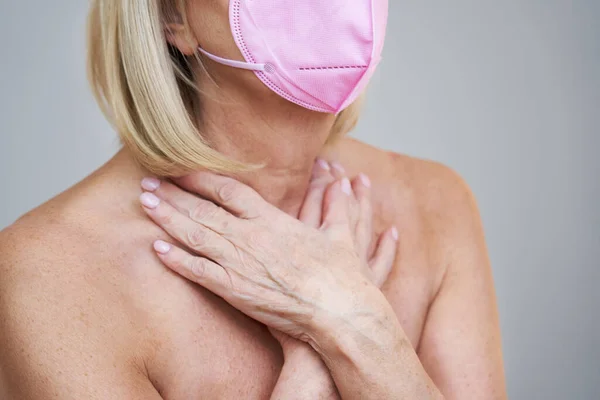 Femme âgée en masque rose posant sur fond gris — Photo