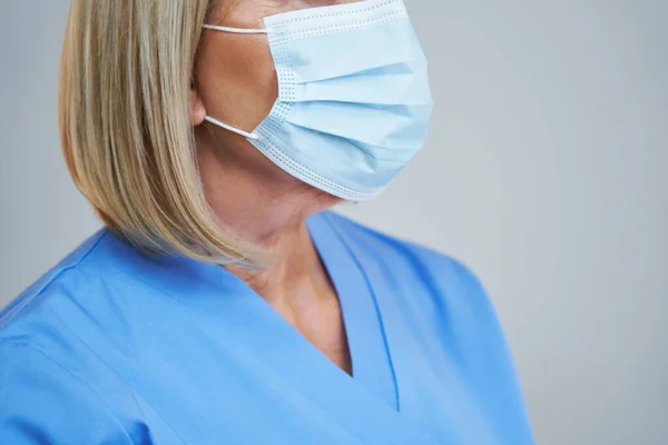 Senior médico femenino posando en máscara sobre fondo gris — Foto de Stock