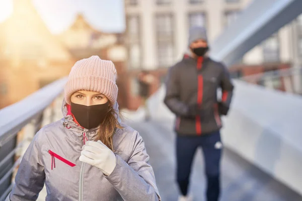 Adult couple jogging in the city in masks during lockdown