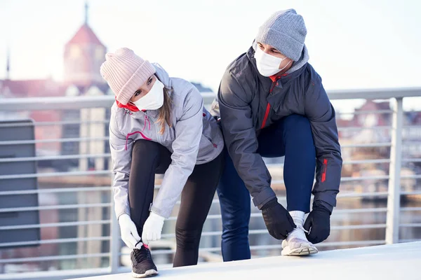 Adult couple jogging in the city in masks during lockdown — Stock Photo, Image