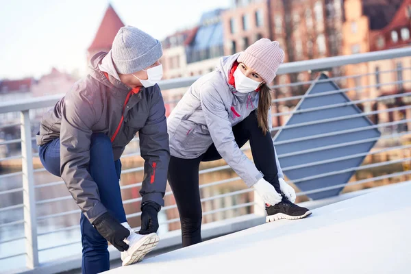 Adult couple jogging in the city in masks during lockdown — Stock Photo, Image