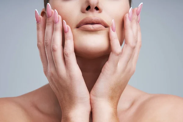 Portret van een mooie vrouw op een grijze achtergrond — Stockfoto