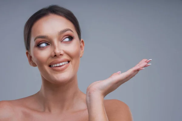 Portret van een mooie vrouw op een grijze achtergrond — Stockfoto