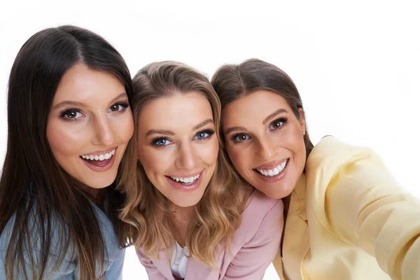 Drie vrouwen in pastel pakken poseren over witte achtergrond — Stockfoto