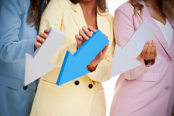 Drie vrouwen in pastel pakken poseren met pijlen over witte achtergrond — Stockfoto