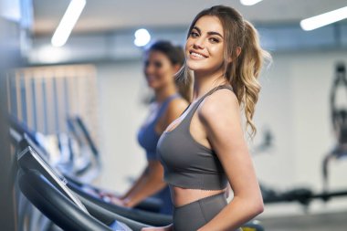 İki kız arkadaş koşu bandında çalışıyor.