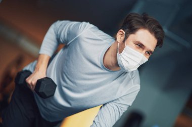 Yetişkin bir adam spor salonunda maske takıyor.