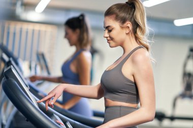 İki kız arkadaş koşu bandında çalışıyor.