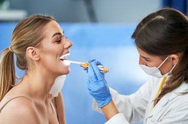 KBB uzmanı kadın hastasını kontrol ediyor.