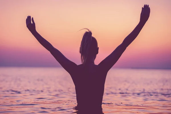 Silhouette de jeune femme pratiquant le yoga sur la plage au lever du soleil — Photo