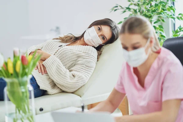 Professional psychiatrist consulting her patient and making notes both in masks — Stock Photo, Image