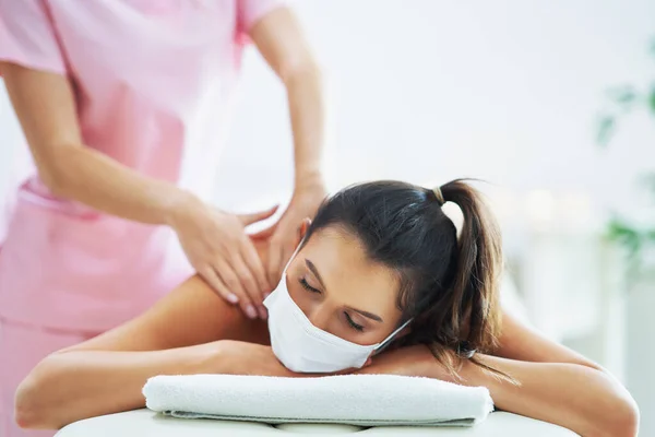 Взрослая женщина в маске во время расслабляющего массажа в спа — стоковое фото