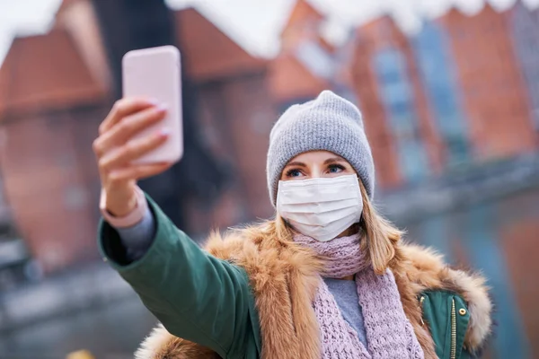 Kvinna bär ansiktsmask och tar selfie i staden — Stockfoto