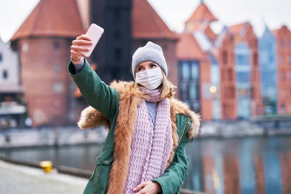 Žena v masce obličeje a brát selfie ve městě — Stock fotografie