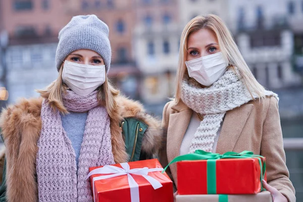 Două femei poartă măști și țin cadouri de Crăciun în oraș — Fotografie, imagine de stoc