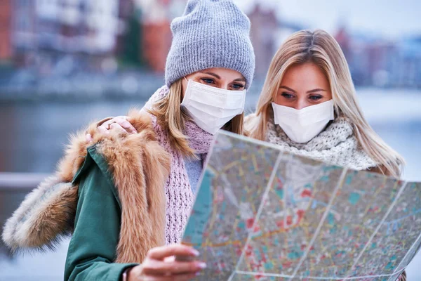 Duas mulheres usando máscaras e segurando mapa enquanto passeia Gdank na Polônia — Fotografia de Stock