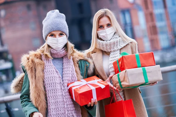Dos mujeres con máscaras y con regalos de Navidad en la ciudad — Foto de Stock