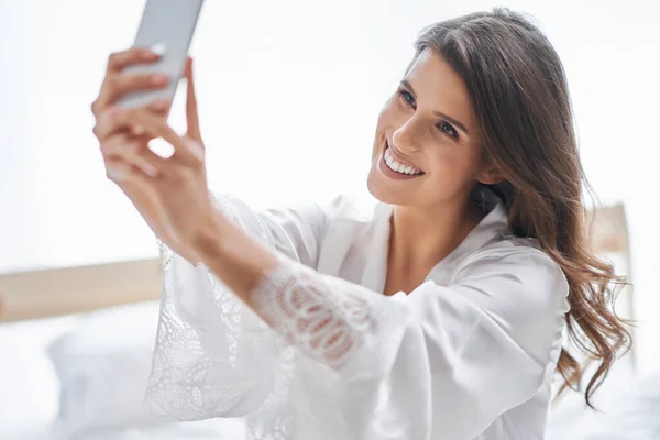 Happyvuxen kvinna använder smartphone i sovrummet på morgonen — Stockfoto