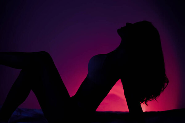 Sexy woman silhouette posing over red dark background. High quality photo