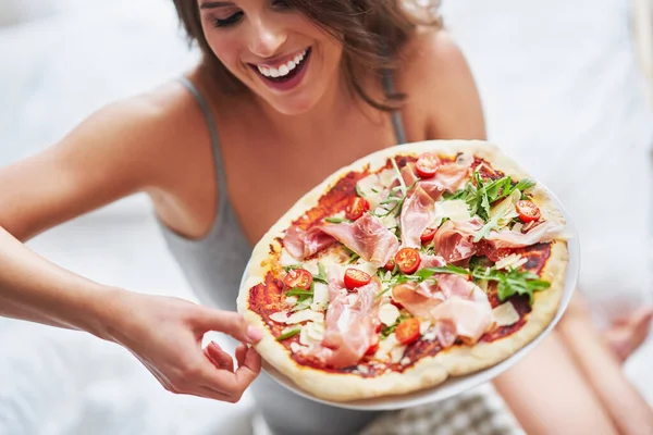 Mooie volwassen vrouw die thuis pizza eet — Stockfoto