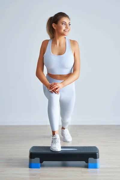 Adulto hermosa mujer trabajando usando stepper hacia fuera sobre fondo claro — Foto de Stock