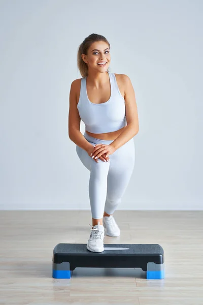 Adulto hermosa mujer trabajando usando stepper hacia fuera sobre fondo claro — Foto de Stock