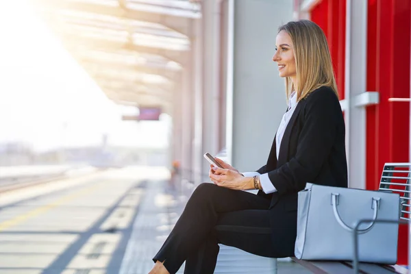 Mujer elegante sentada y esperando el tren en la estación de tren —  Fotos de Stock