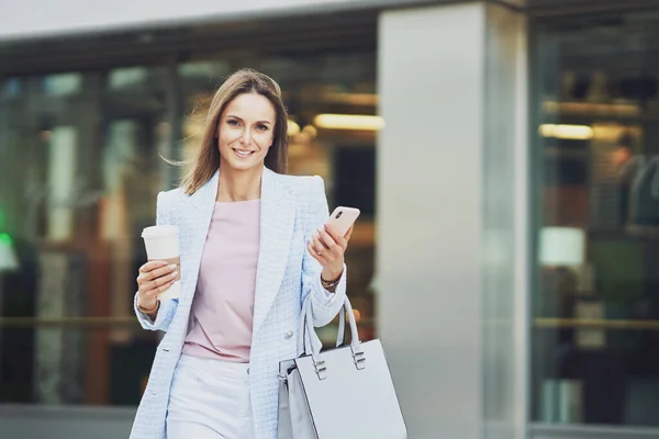 Vuxen attraktiv kvinna med smartphone promenader i staden — Stockfoto