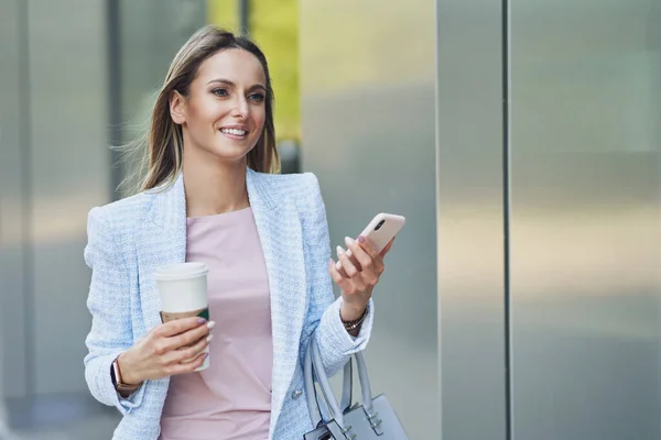 Mujer atractiva para adultos con smartphone caminando en la ciudad —  Fotos de Stock