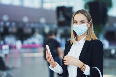 Havaalanında akıllı telefon kullanan yetişkin bir bayan yolcu.