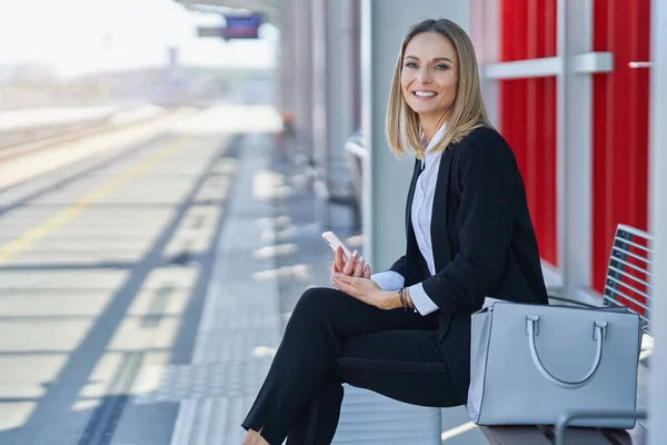 Elegante vrouw zit en wacht op de trein in het station — Stockfoto