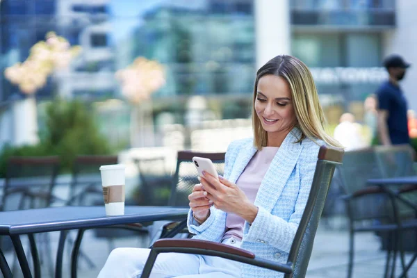 Dospělá atraktivní žena pomocí smartphonu a relaxaci ve městě — Stock fotografie