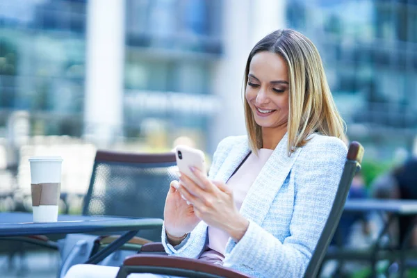 Adulto mulher atraente usando smartphone e relaxante na cidade — Fotografia de Stock