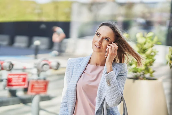 Adulto mulher de negócios atraente com smartphone andando na cidade — Fotografia de Stock