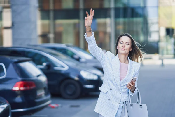 Zakelijke vrouw neemt een taxi in de stad — Stockfoto