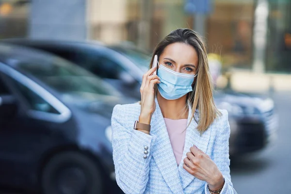 A woman in mask talking on a cell phone — Stock Photo, Image