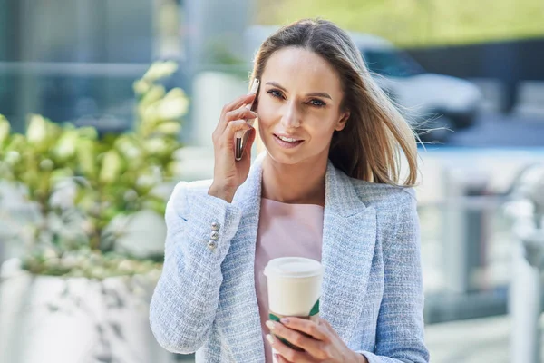 Adulto atraente Mulher de negócios com smartphone e café andando na cidade — Fotografia de Stock