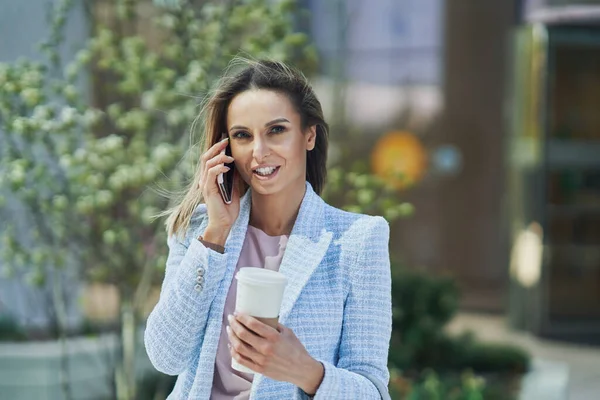 Adulto atraente Mulher de negócios com smartphone e café andando na cidade — Fotografia de Stock